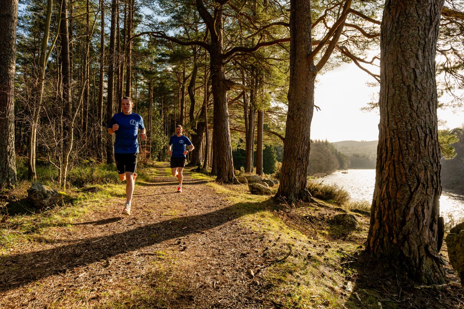 Runners on a riverside forest trail
